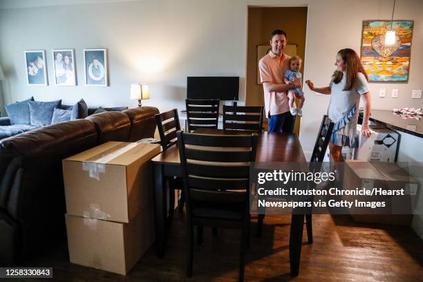 Nick and Aly O'Neal, with their 8-month-old son, Shepherd, work around moving boxes as they are preparing to close on a house in Sugar Land and will...