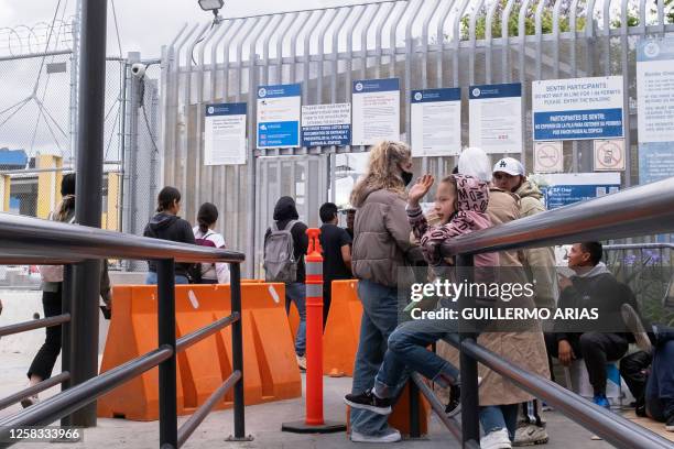 An asylum seeker girl from Russia waves people crossing the border while waiting for US Customs and Border Protection agents to allow her enter the...