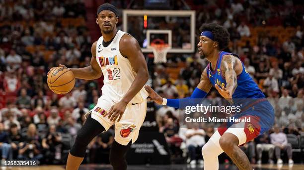 Miami Heat forward Jimmy Butler dribbles while Denver Nuggets guard Kentavious Caldwell-Pope defends during the first quarter of an NBA game at...