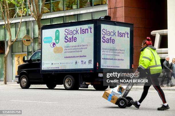 Pedestrians pass a vehicle displaying a mobile billboard calling on Slack to offer end-to-end encryption, outside the Slack offices in San Francisco,...