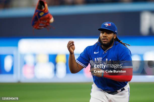 Vladimir Guerrero Jr. #27 of the Toronto Blue Jays throws his glove with a ball stuck in it to Trevor Richards for an out in the fifth nning of their...