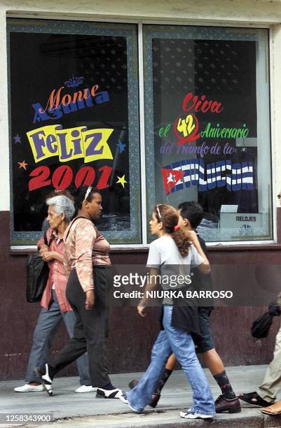 Cuban pass in front of the decorated window with sign which makes reference to the new millenium in the center Habana, Cuba, 28 December 2000. The...