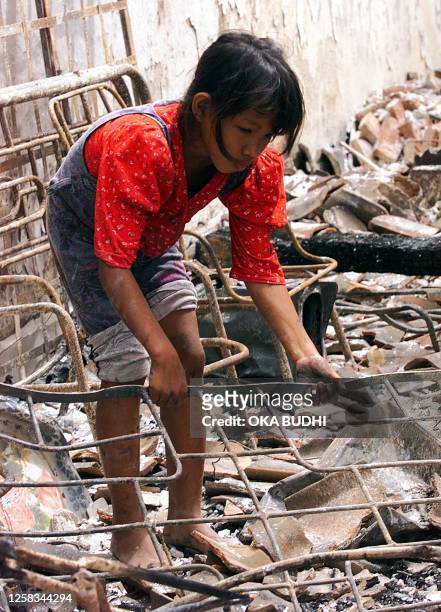 An Indonesian girl collects metal from a burned shop at Ampenan on the island of Lombock 20 January 2000 after religious violence swept across the...