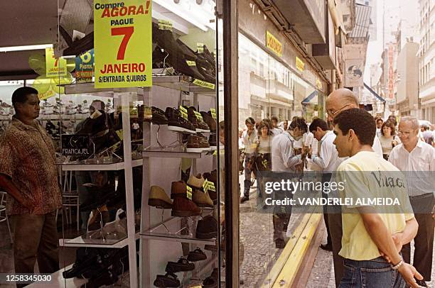 Habitantes de Rio de Janeiro miran 10 de Noviembre a la vidriera de una tienda de zapatos que anuncia ventas con la primera cuota para el 07 de Enero...