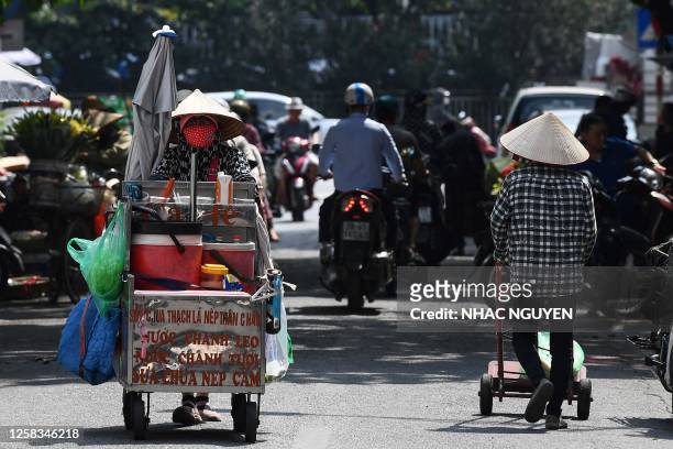 Street vendor Vu Thi Phuong pushes her trolley to sell coffee and soft drinks in Hanoi on June 1, 2023. Thousands of street vendors, largely women,...
