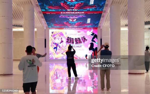 Customers watch an LED screen promoting the movie Spider-Man: Across the Universe at Shanghai Cinema in Shanghai, China, May 31, 2023. A spiral...