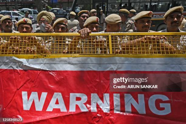 Policemen stand guard behind a barricade during a demonstration by the members of the Indian Youth Congress in support of Indian wrestlers protesting...