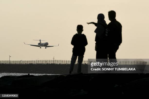 People watch a plane landing at Ngurah Rai international airport in Denpasar on Indonesia's resort island of Bali on June 1, 2023.