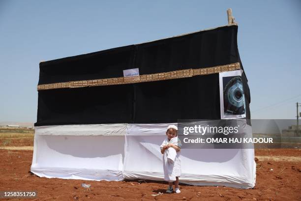 Child stands in front of a makeshift replica of the Kaaba -- the large black cubic structure at the centre of the Grand Mosque in Mecca -- during a...