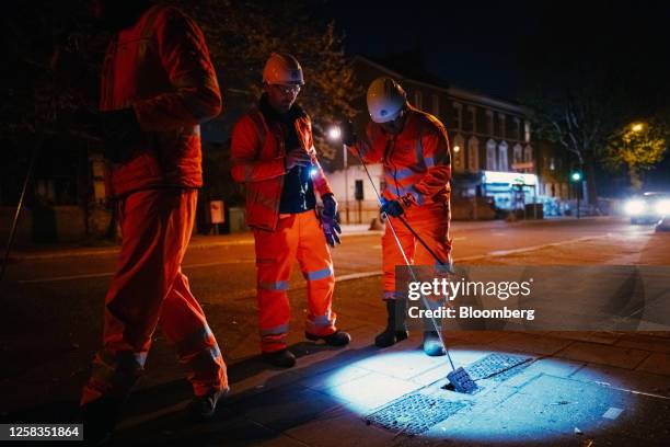 Engineers from a Thames Water leak hunting team lift a maintenance hole cover while searching for leaks during the crew's night shift in London, UK,...