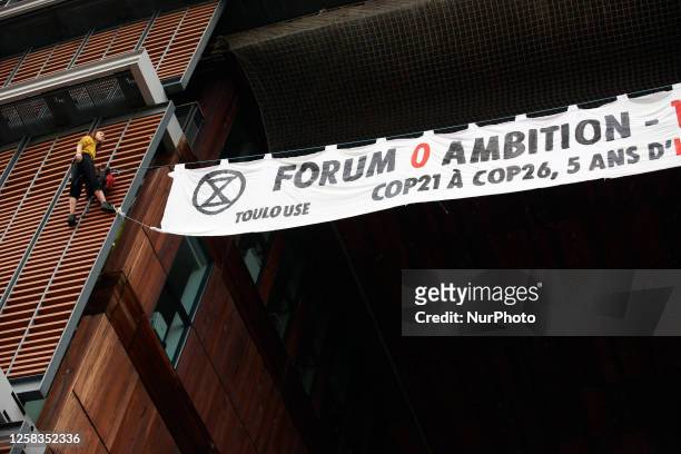 Two climbers from XR Toulouse climbed on the facade of the Mediatheque of Toulouse to put a banner reading ' 0 ambition forum - 100% greenwashing,...
