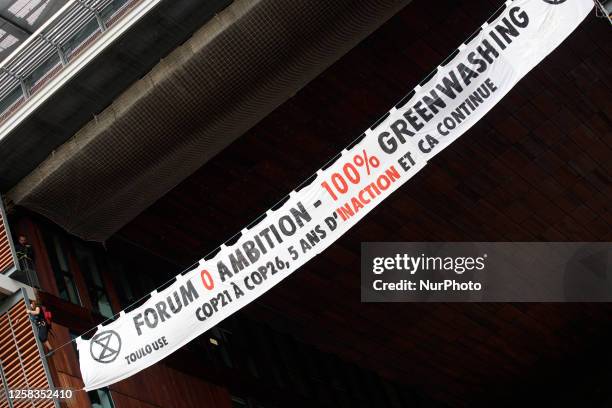 Two climbers from XR Toulouse climbed on the facade of the Mediatheque of Toulouse to put a banner reading ' 0 ambition forum - 100% greenwashing,...