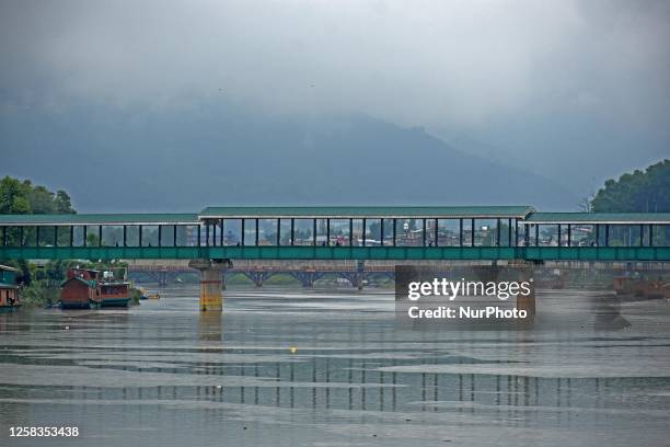 People cross the foot bridge as it rains in Srinagar,Kashmir on June 01, 2023. Rains continued across Jammu and Kashmir leading to the drop in...