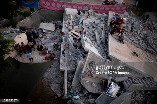 Palestinians stand on the rubble of their home destroyed by Israeli airstrikes in Beit Lahiya, in the northern Gaza Strip, during the latest five-day...