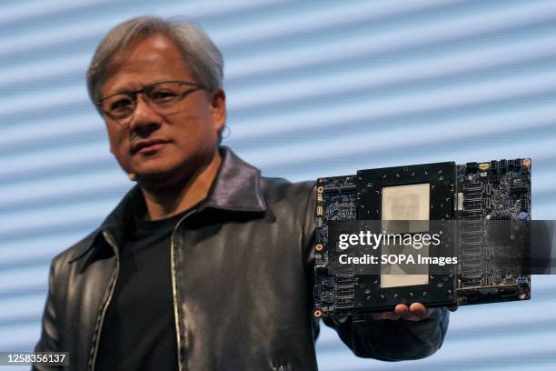 Jensen Huang, President of NVIDIA holding the Grace hopper superchip CPU used for generative AI at supermicro keynote presentation during the...