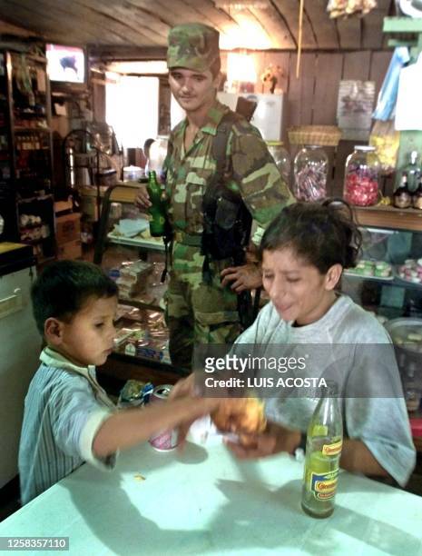 Rebel with the Revolutionary Armed Forces of Colombia watches a woman and her son in a store 13 February in Los Pozos, Colombia. Colombian government...
