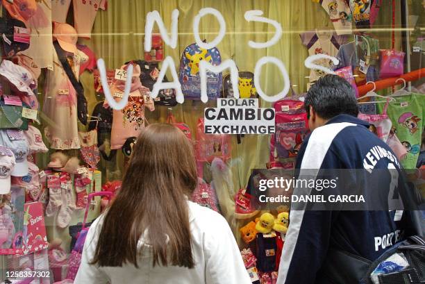 Couple looks at a window display at a childrens store offering to exchange money, 20 March 2002 in Buenos Aires. Una pareja observa la vidriera de un...