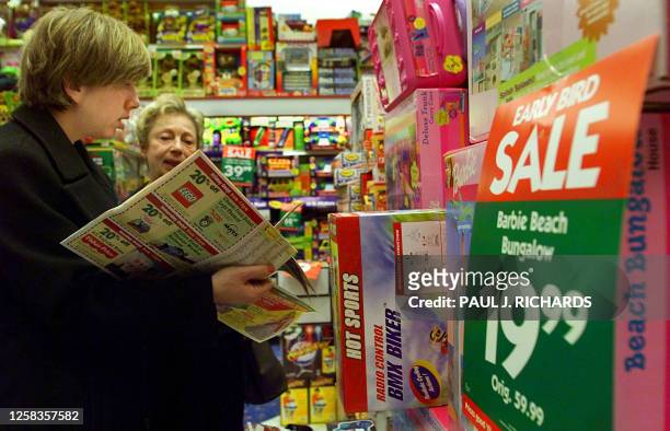 Debra and Jerri-Ann David check their holiday shopping advertisements as the shop for Barbie Doll accessories at the K-B Toy store 23 November 2001,...