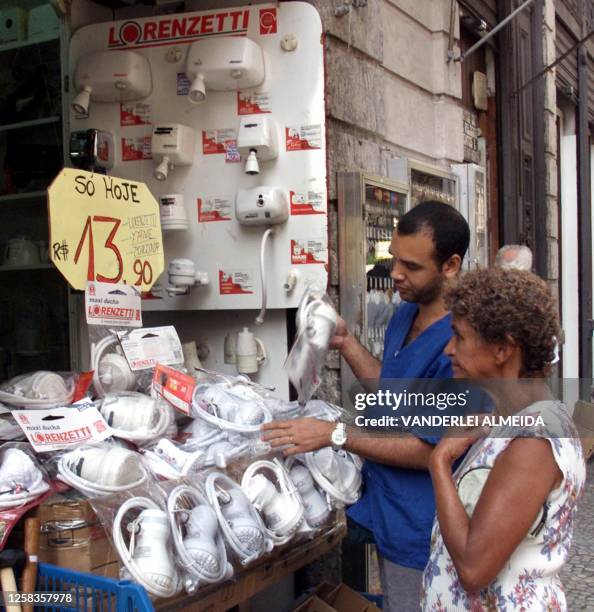 Salesman shows electric showers to a client, 31 May 2001, in a store in Rio de Janeiro, Brazil. Un vendedor le muestra duchas electricas a una...
