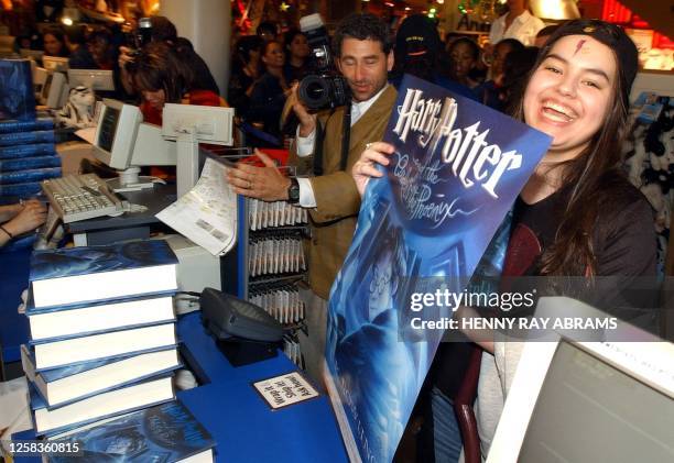 Harry Potter fan Caitlin Messina of Ridgefield, Connecticut, holds up the free poster she received while purchasing the latest edition in the series,...