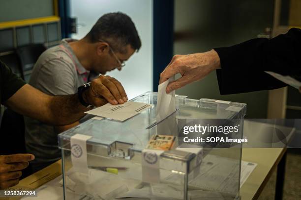 Voter drops his ballot to a ballot box in one of the polling stations. People in Barcelona went to their respective polling stations to cast their...