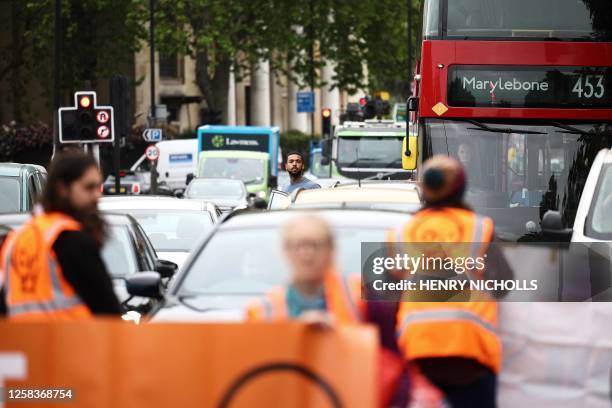 Commuter steps out of a car to look at Just Stop Oil climate activists marching in London on June 2, 2023 as part of their campaign calling on the UK...