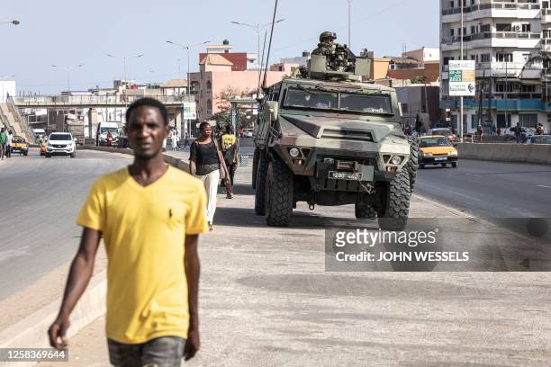 People walks past members of the Senegalese Armed Forces patrolling the streets in Dakar, on June 2, 2023 following violent protests. A court in...