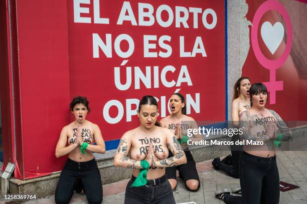 Activists of feminist group FEMEN with their bare chests painted with messages reading "You don't pray, you harass" and "abortion is sacred"...