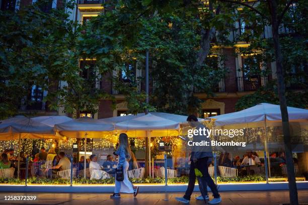 Pedestrians pass customers dining on a restaurant terrace in the Salamanca district of Madrid, Spain, on Saturday, May 27, 2023. A flood of funds...