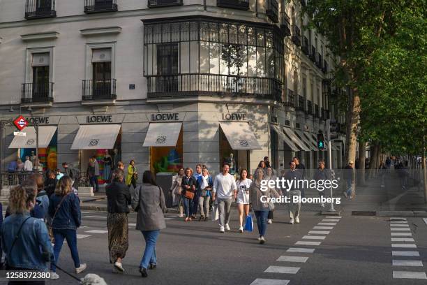 Pedestrians and shoppers cross a street at a Loewe SA luxury store, operated by LVMH Moet Hennessy Louis SE, in the Salamanca district of Madrid,...