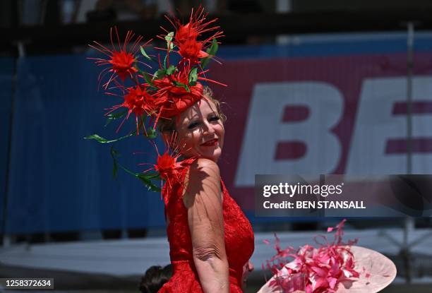 Racegoer poses for a photograph in the sunshine on the first day of the Epsom Derby Festival horse racing event in Surrey, southern England on June...