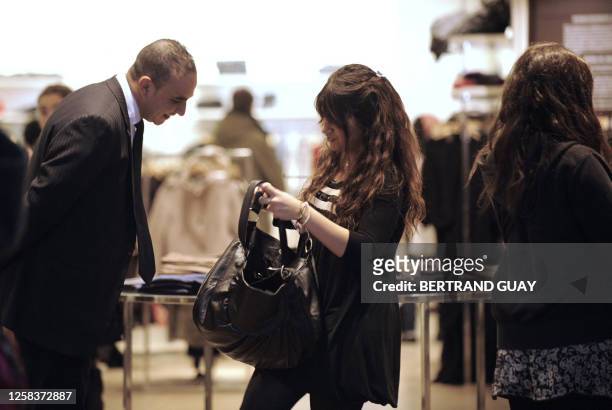 Security man checks the bags of a shopper on December 17, 2008 in a shop close to Le Printemps, one of Paris's top department stores, a day after an...