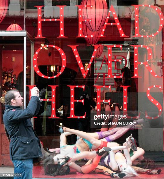 Man takes pictures as he walks past an Agent Provocateur shop 16 November 2007 in a street of London. Agent Provocateur, a leading player in the...