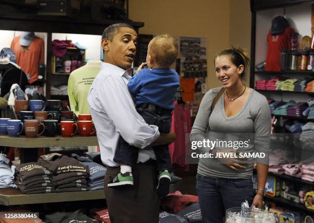 President Barack Obama holds a child as he buys candies at the Mast General store in Boone, North Carolina, on October 17, 2011 during the first day...