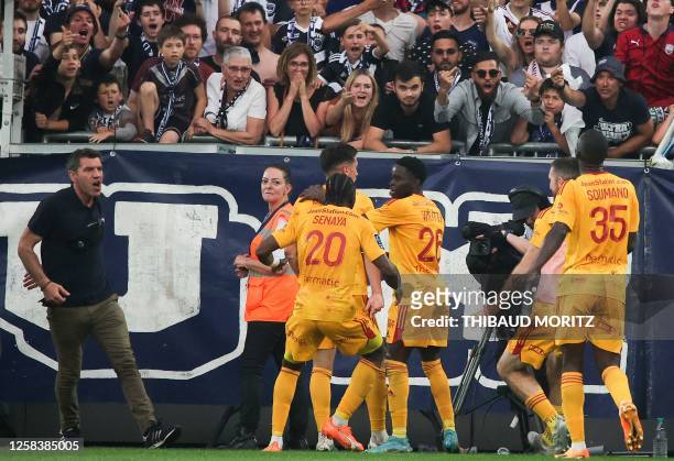 Rodez' players celebrate after scoring a goal as a spectator enters the pitch and runs towards them during the French L2 football match between FC...