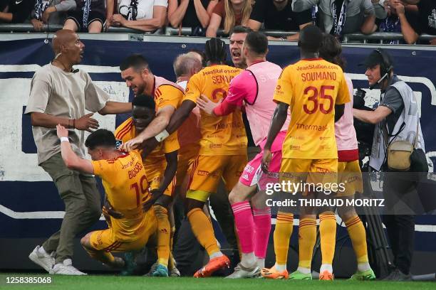 Rodez' French midfielder Lucas Buades celebrates with teammates after scoring a goal as a spectator scuffles with players after entering the pitch...