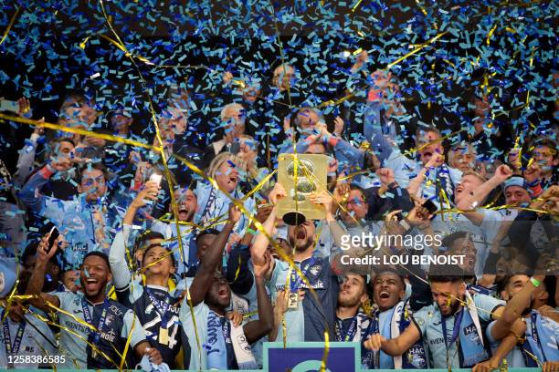 Le Havre's Algerian midfielder Victor Lekhal holds up the trophy as Le Havre players celebrate their French L2 championship after the football match...