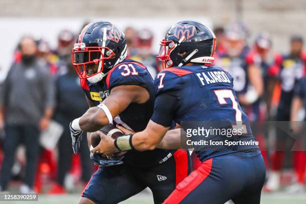 Hamilton Tiger-Cats defensive back Javien Elliott hands the ball off to Montreal Alouettes running back William Stanback during the Hamilton...