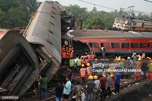 Rescue workers gather around damaged carriages at the accident site of a three-train collision near Balasore, about 200 km from the state capital...