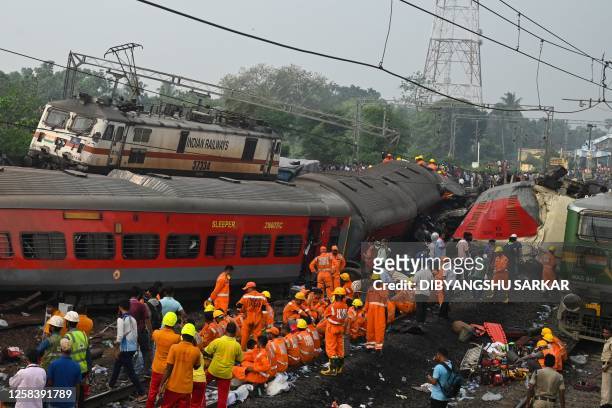 Rescue workers gather around damaged carriages at the accident site of a three-train collision near Balasore, about 200 km from the state capital...