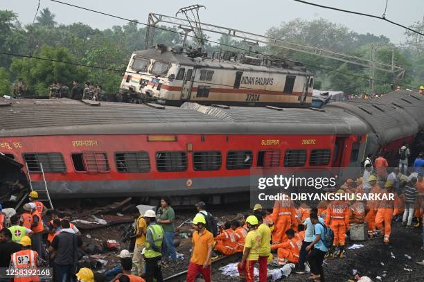 Rescue workers and military personnel gather around damaged carriages at the accident site of a three-train collision near Balasore, about 200 km...