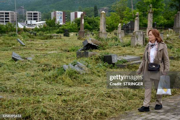 Woman walks past vandalized graves at the Orthodox cemetery in the ethnically divided Kosovo town of Mitrovica, on June 3, 2023. Serbs from the north...