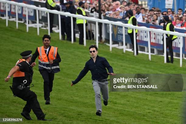 Protester runs onto the racecourse before being apprehended by police officers ahead of the arrival of the Derby field on the second day of the Epsom...