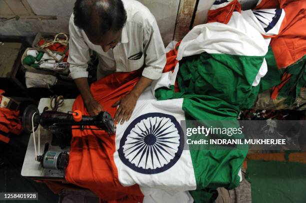 Indian veteran tailor Abdul Gaffar Shaikh, who has been stitching flags for the last 19 years, aligns a national flag by his sewing machine at a...