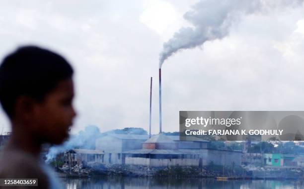 Young Bangladeshi boy looks towards the smoke belching chimney of a battery re-cycling plant on the banks of the river Buriganga in Dhaka, 26...