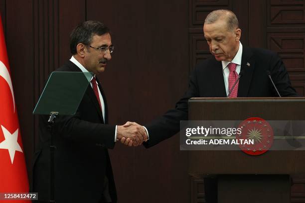 Turkey's President Recep Tayyip Erdogan shakes hands with Turkey's new Vice-President Cevdet Yilmaz as he unveils the country's new cabinet at...