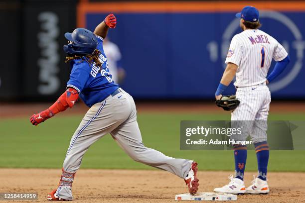 Vladimir Guerrero Jr. #27 of the Toronto Blue Jays reacts after hitting an RBI double as Jeff McNeil of the New York Mets looks away during the ninth...