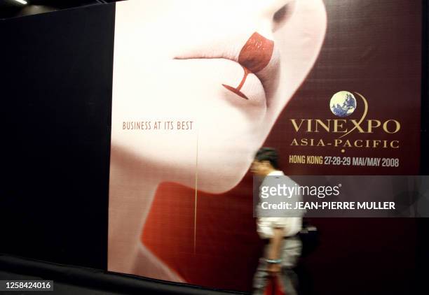 Visitor walks past a poster for the 2008 Vinexpo show in Hong-Kong, 19 June 2007 during the world's biggest wine and spirits trade fair in Bordeaux,...