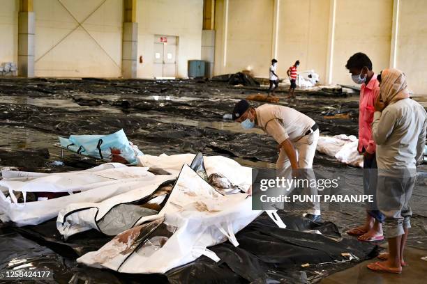 Graphic content / A policeman helps a man to identify his family member's body at a business park used as temporary mortuary for the dead recovered...