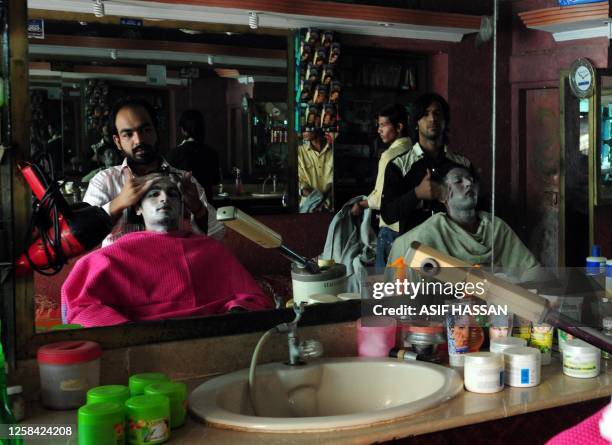Pakistani beautician apply facial beauty treatments on male customers at a beauty salon in Karachi on January 22, 2011. The "metrosexual male" is on...